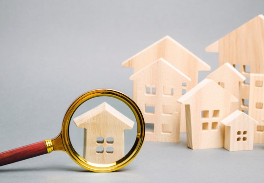Magnifying glass and wooden houses. House searching concept. Home appraisal. Property valuation. Choice of location for the construction. Search for housing, apartments. Real estate appraiser services