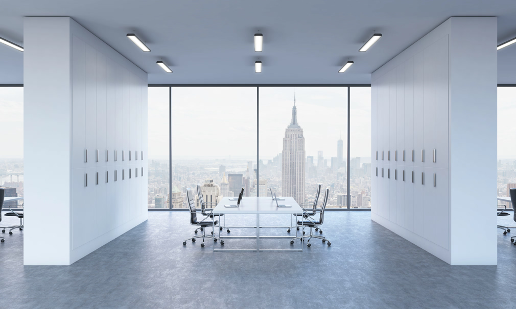Workplaces in a bright modern open space office. White tables equipped by modern laptops and black chairs. New York panoramic view. 3D rendering.