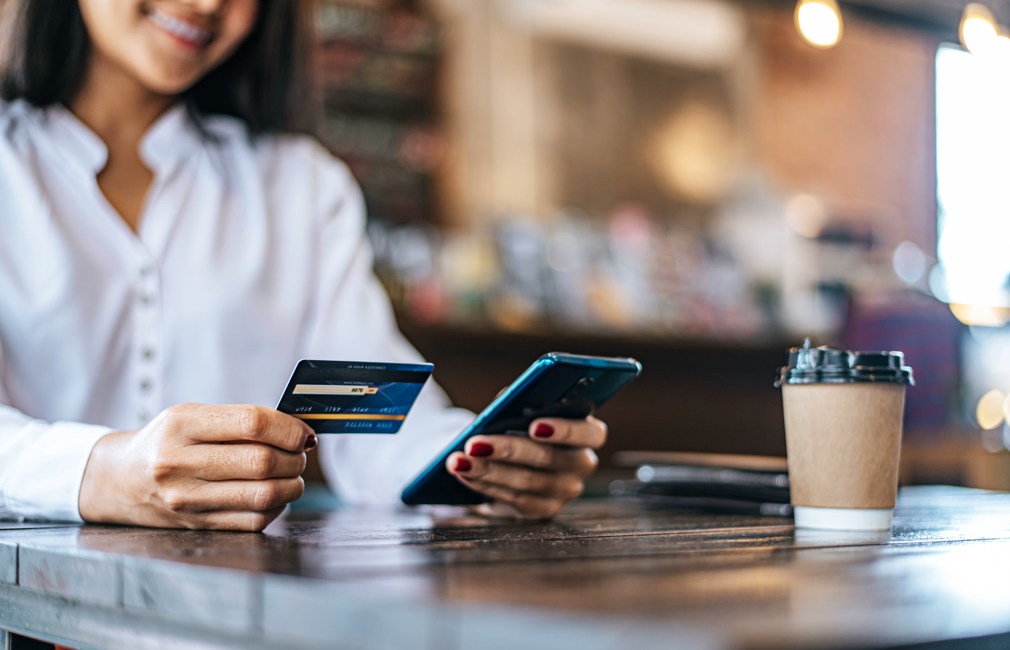 Pay for goods by credit card through a smartphone in a coffee shop.