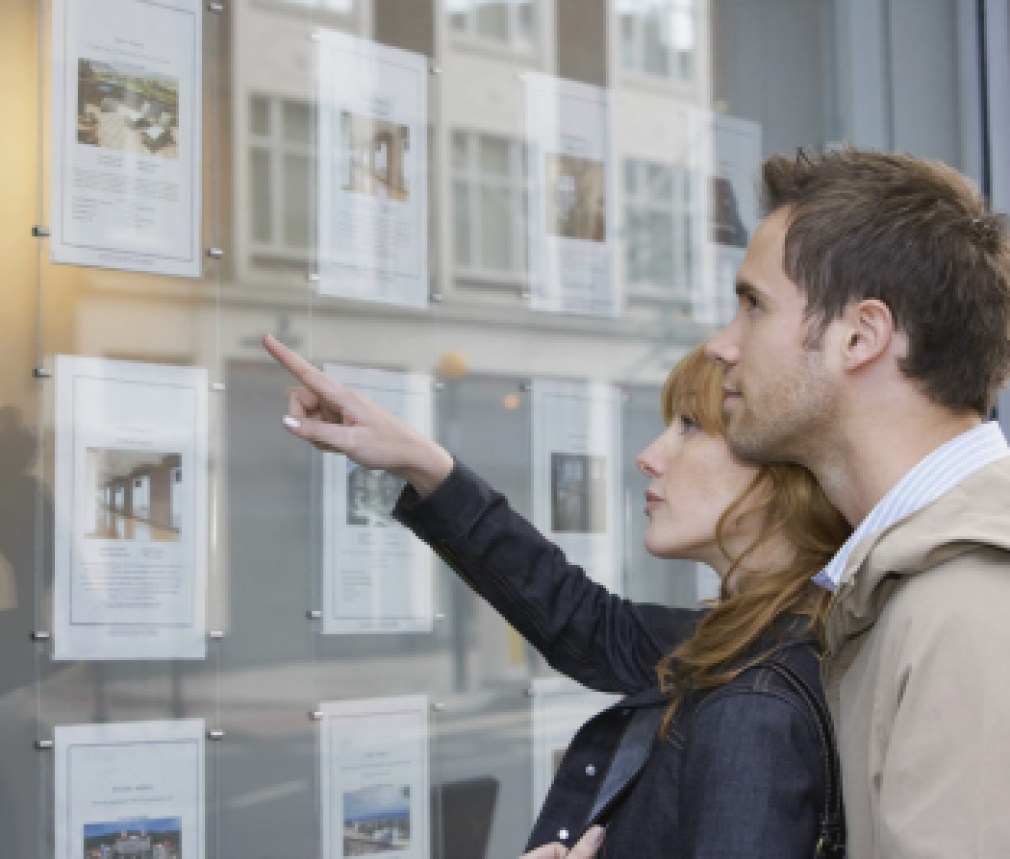 Side view of a young couple looking at window display at real estate office