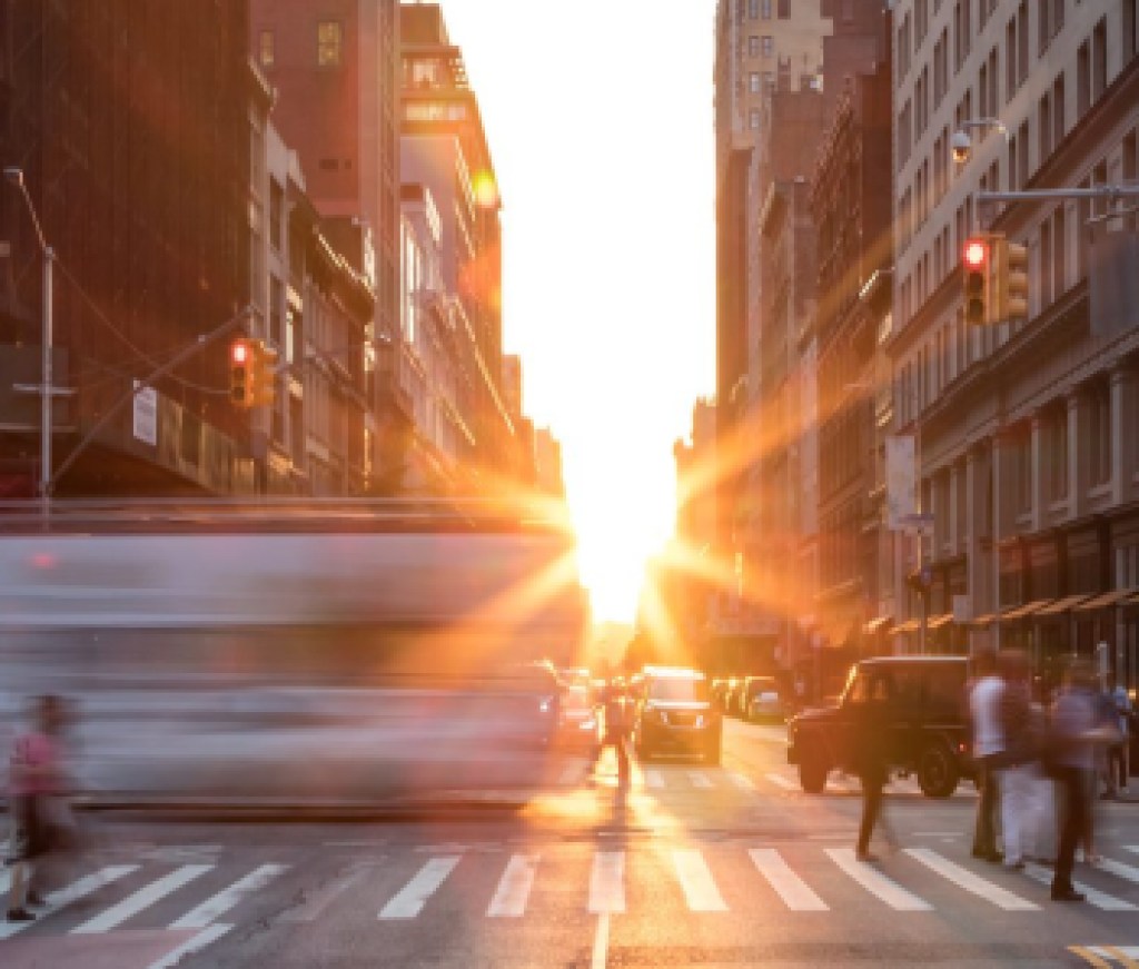 Busy New York City street scene with crowds of people in Midtown Manhattan with sunset background