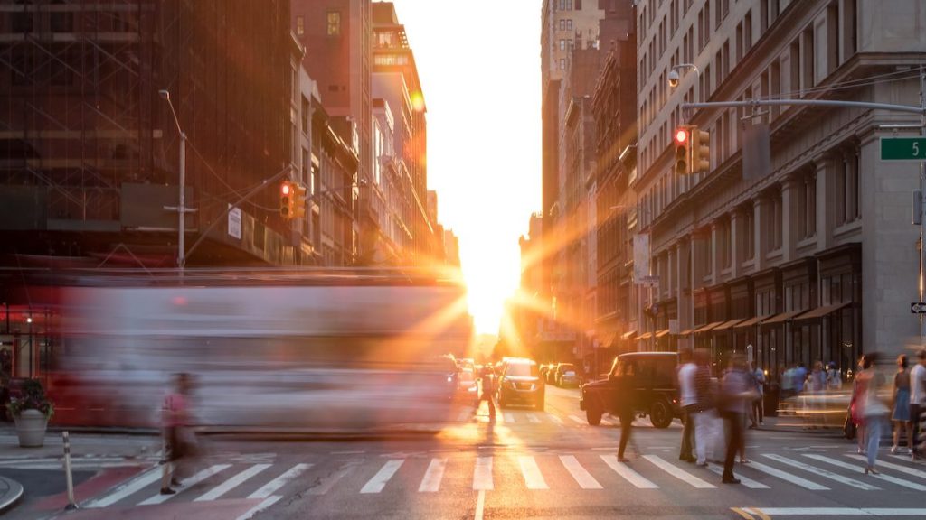 Busy New York City street scene with crowds of people in Midtown Manhattan with sunset background