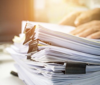 Businessman hands searching data information in Stack of papers files on work desk in office, business report paper or piles of unfinished documents achives with clips on offices indoor, Business concept