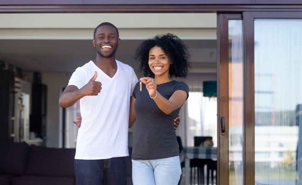 African couple standing on terrace hold keys of new house