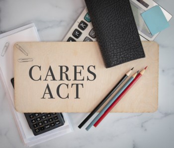 Cares Act sign on wooden sign with office materials laying around government financial aid programs small business relief