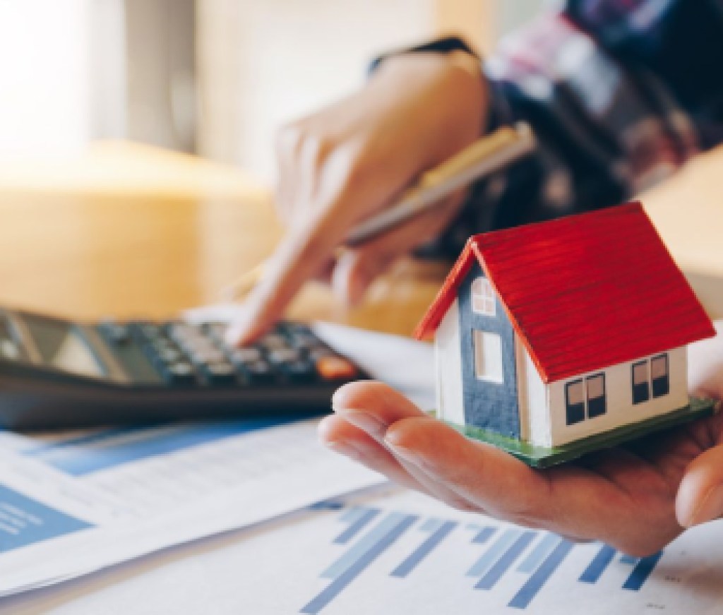 Woman holding house model in hand and calculating financial chart for investment to buying property.