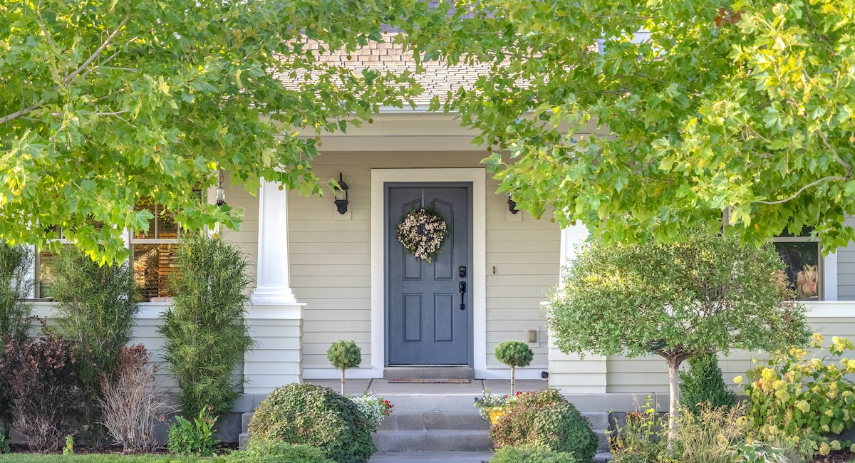 Front door of a home surrounded by leafy trees