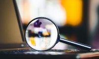 Magnifying glass on laptop keyboard. Internet security concept background.