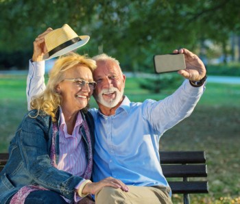 Senior couple taking a selfie photo with smart phone in a park
