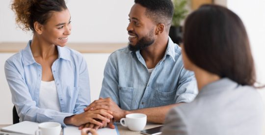Smiling african american couple holding hands in financial advisor's office
