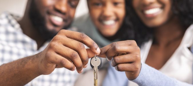 Happy african american family holding keys from their new home