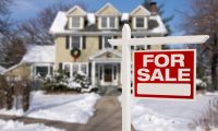 red and white for sale sign in front yard of large house with christmas decorations in winter