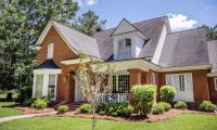 two story brick house next to forest