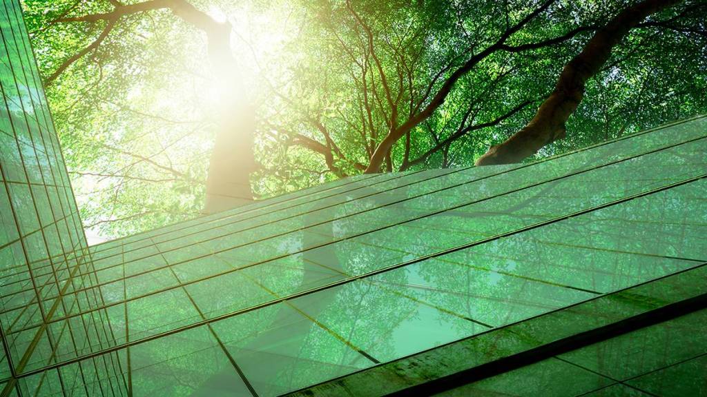 Green building real estate niche; picture...a very modern glass home reflecting beautiful green trees above it