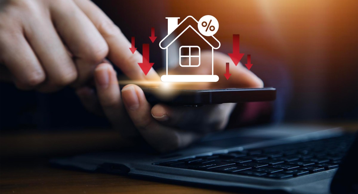 Businessman use smartphone with virtual home icon and down arrow for economical real estate and lower mortgage interest rates. Reduced prices for rental housing, Demand for home purchases decreases.