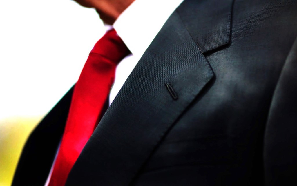 a black business suit jacket with white shirt and red tie, man n