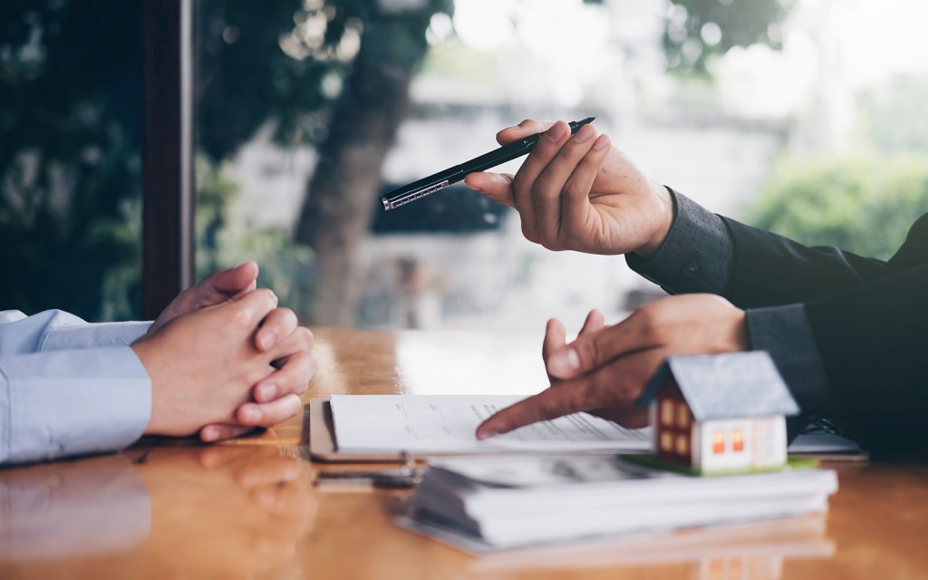 real estate agent holding house key to his client after signing